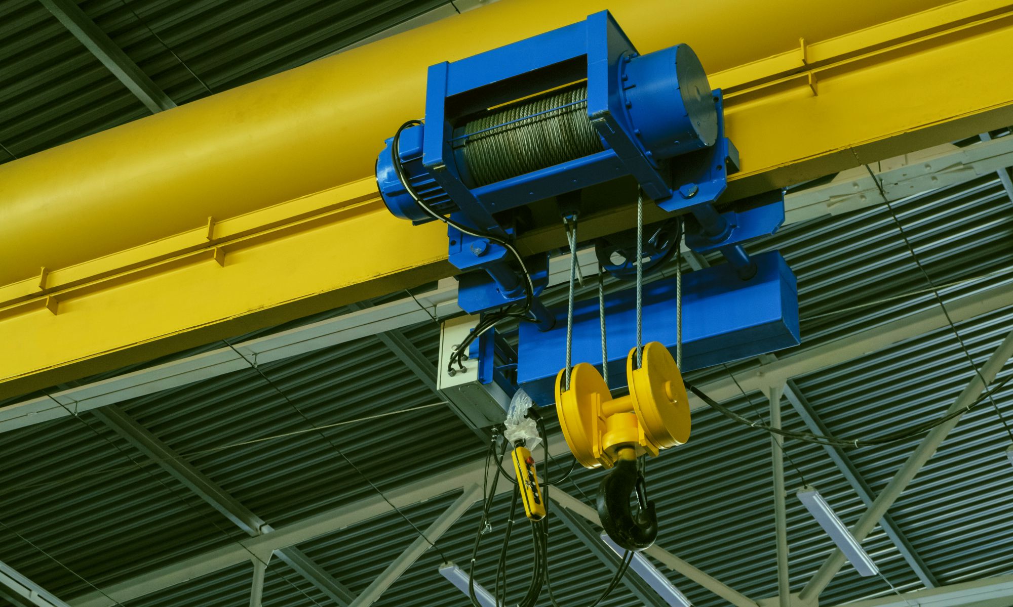 Moving crane rig on ceiling used for material handling at factory.